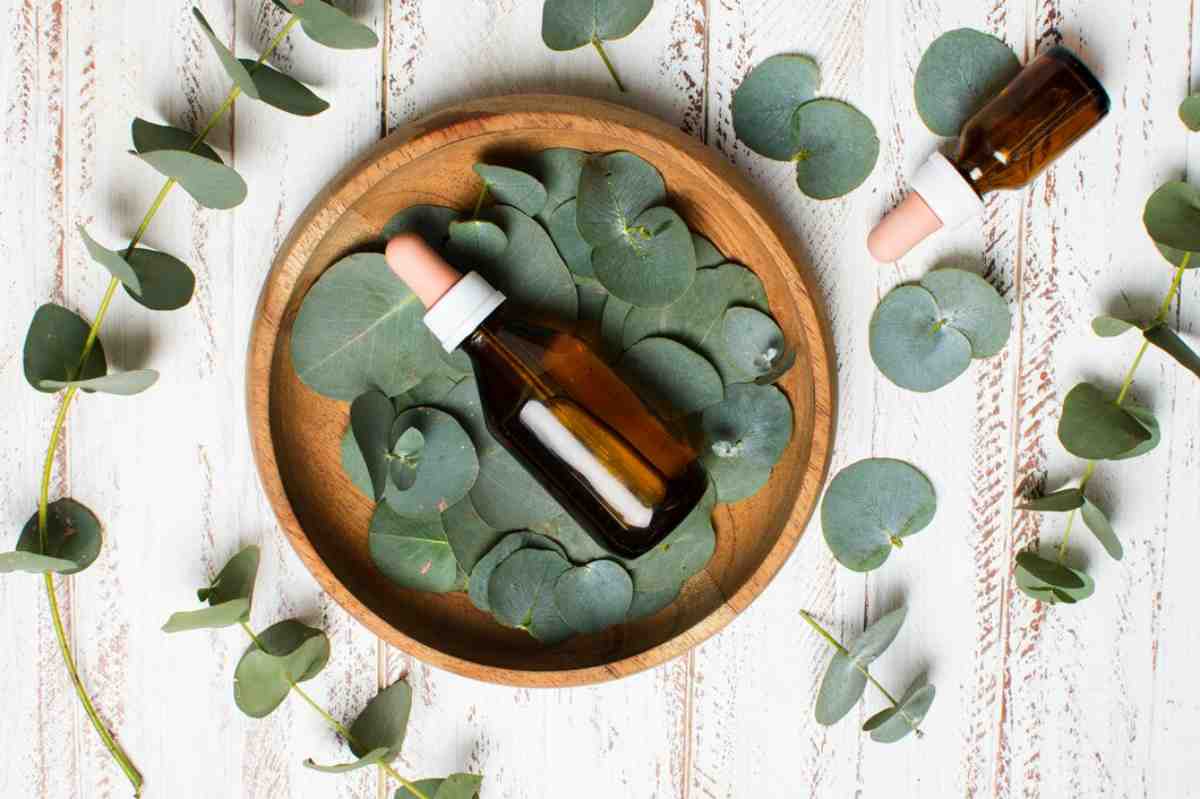 wooden bowl filled with eucalyptus leaves, featuring two amber dropper