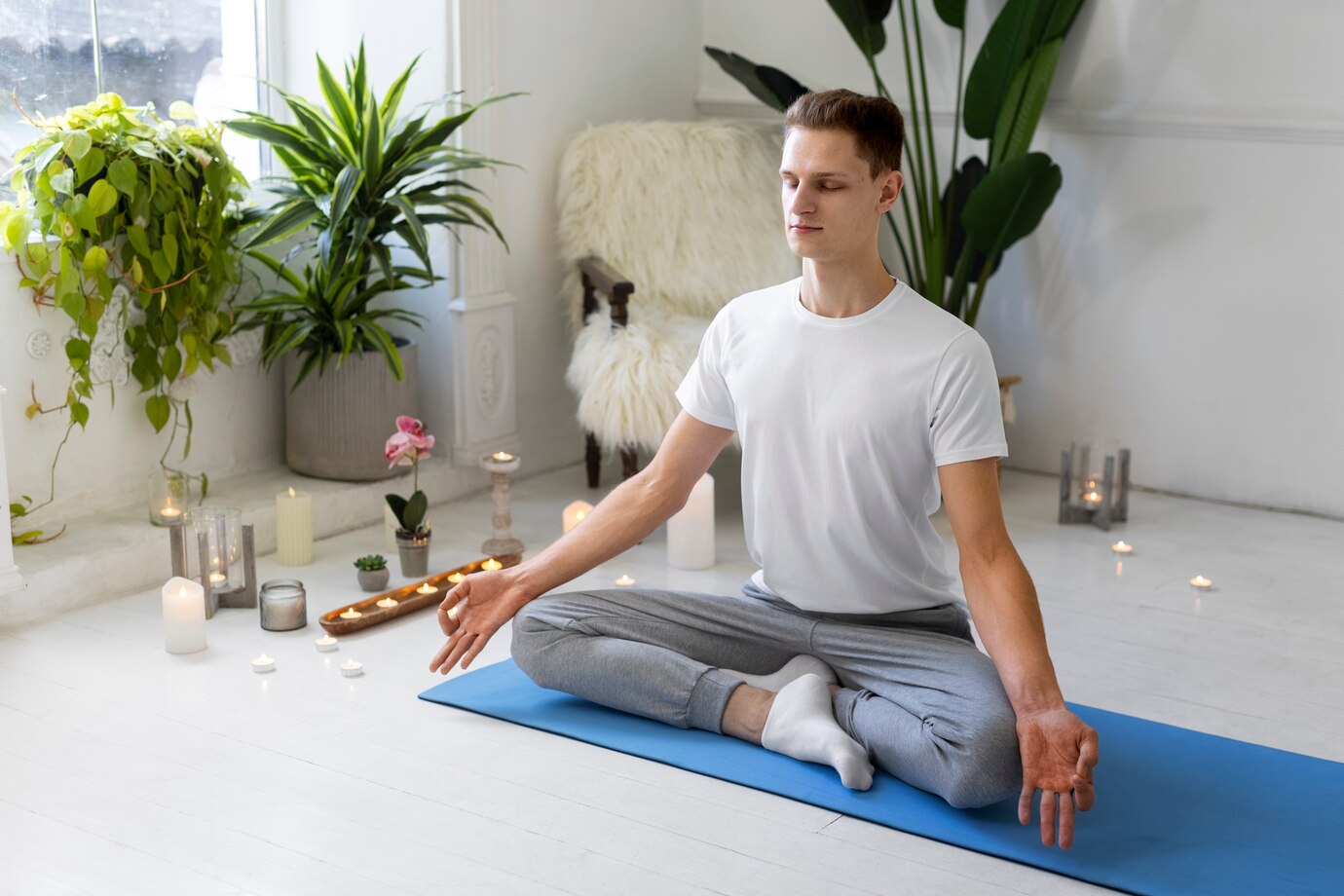 A young man meditating in a serene indoor setting 