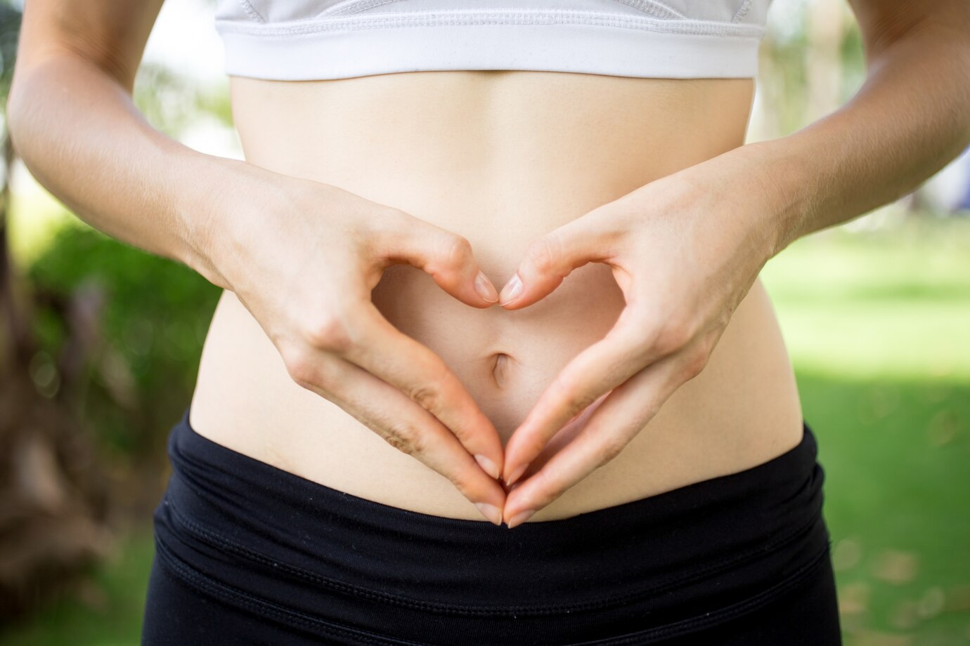  person forms a heart shape with their hands over their bare stomach