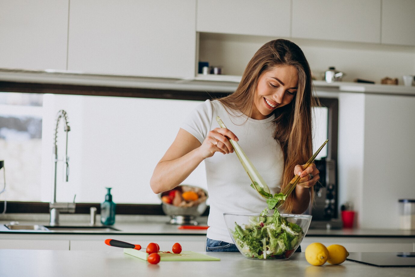  young woman happily preparing a salad in a modern kitchen