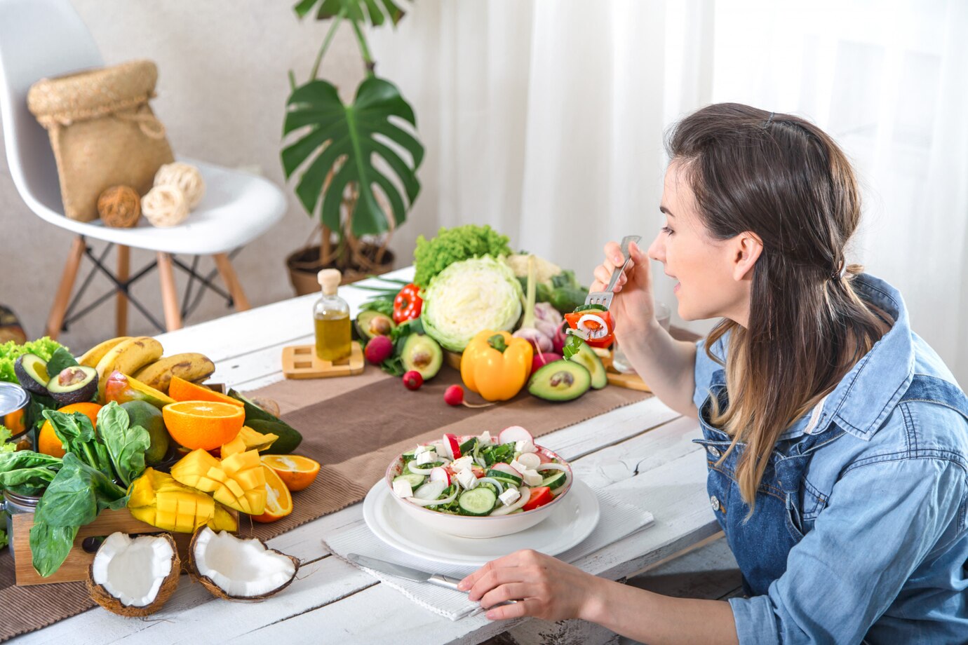  woman eating a healthy salad at a table filled with various fresh fruits