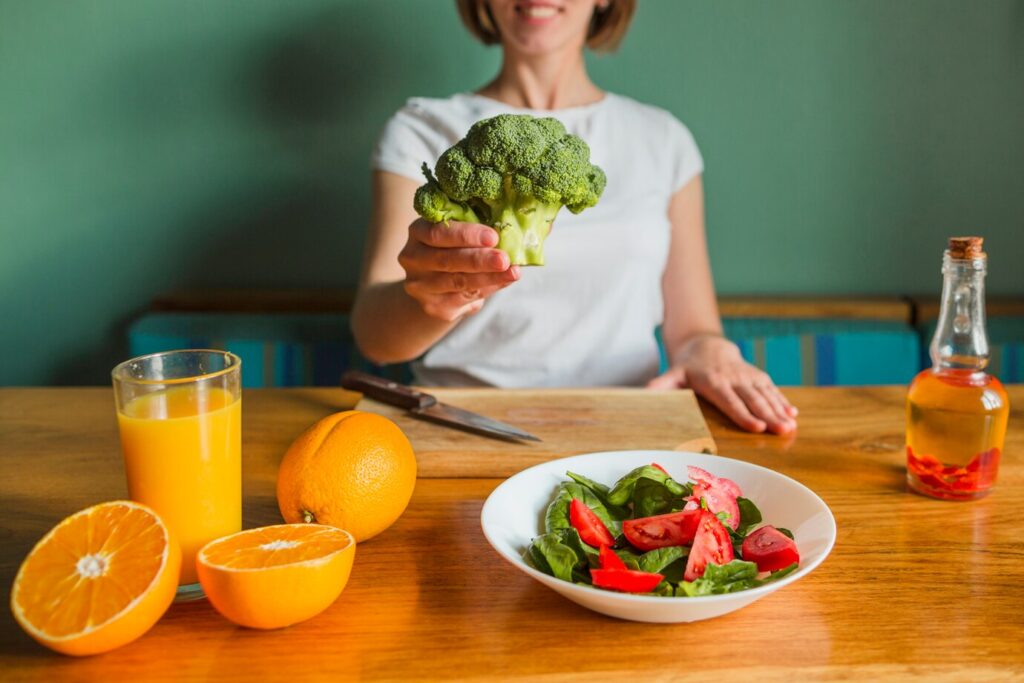 A fresh salad, orange juice, and oranges are on a wooden table
