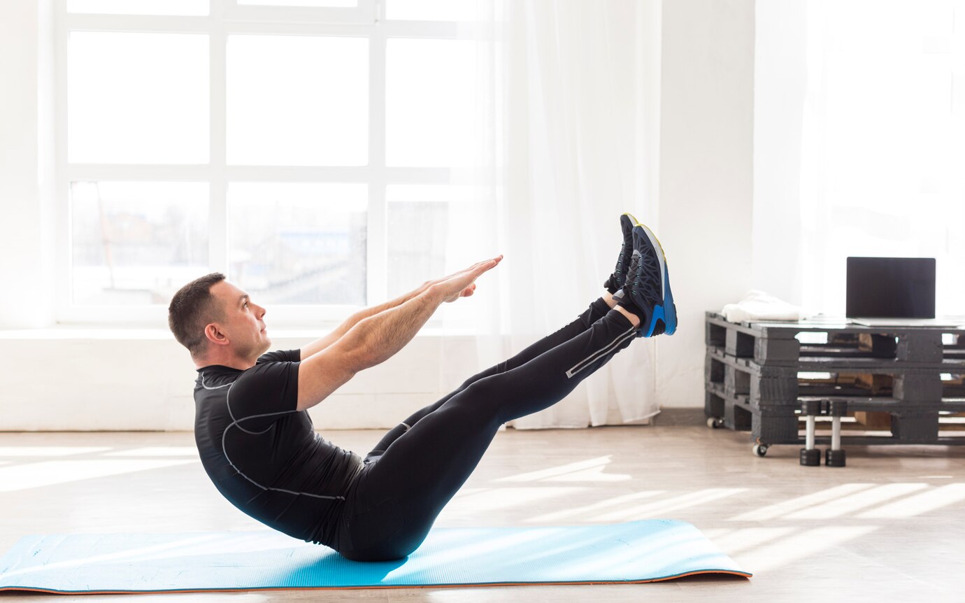 Man performing a V-sit exercise on a blue mat