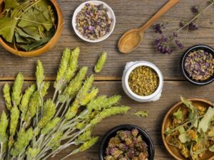 Overhead view of various dried herbs and flowers scattered on a wooden surface