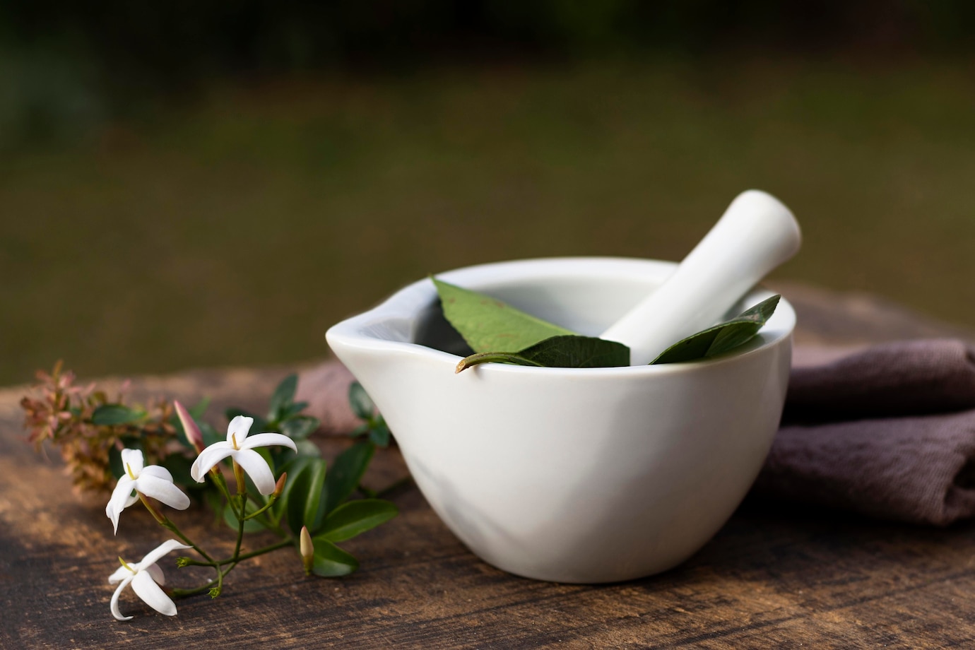white ceramic mortar and pestle containing fresh green leaves