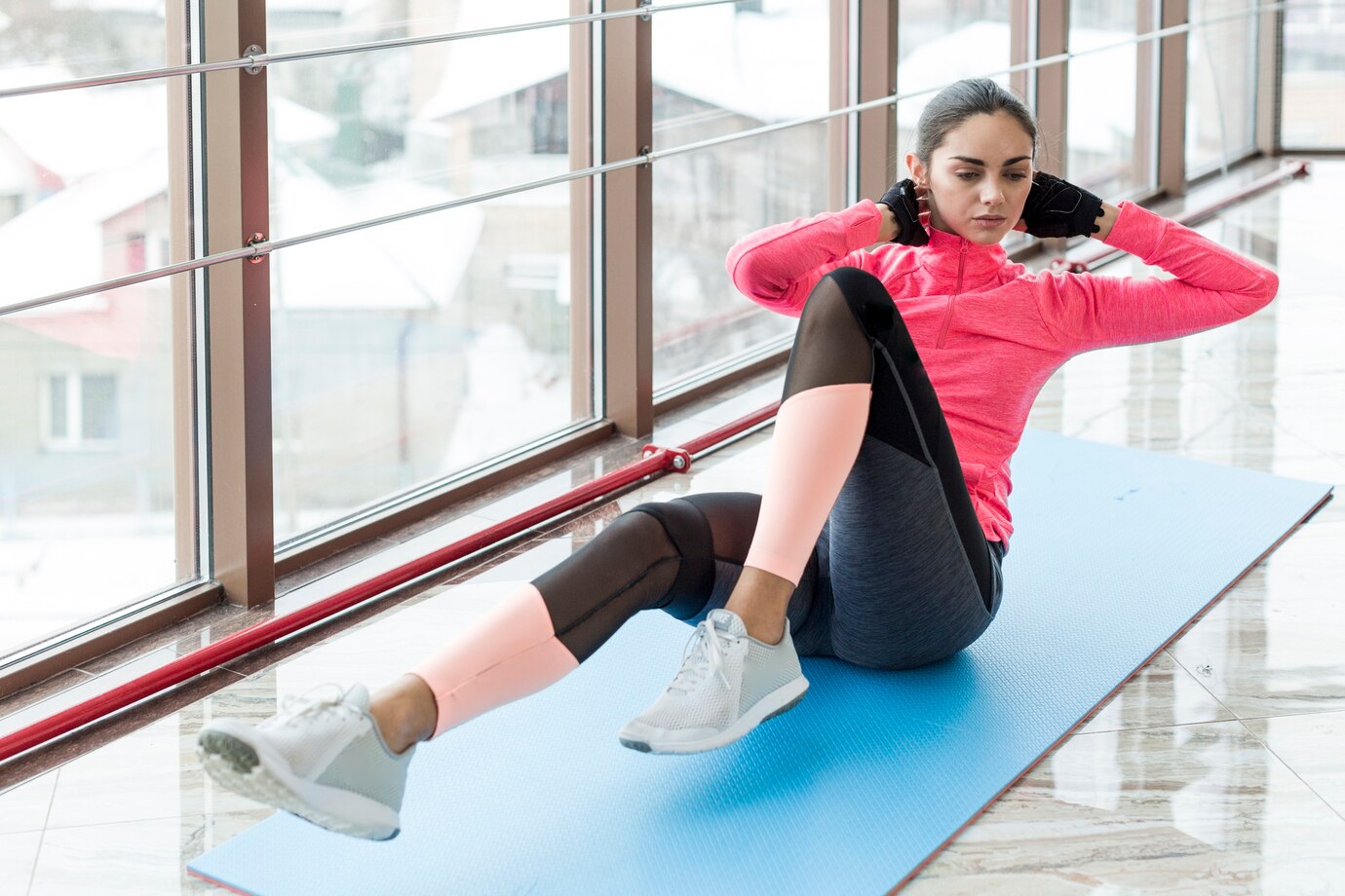 Woman in pink and black athletic wear performing a sit-up exercise