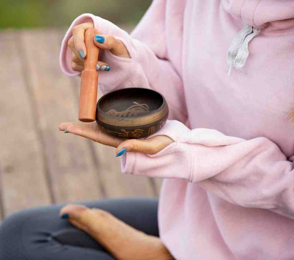 Person holding a Tibetan singing bowl and a wooden mallet