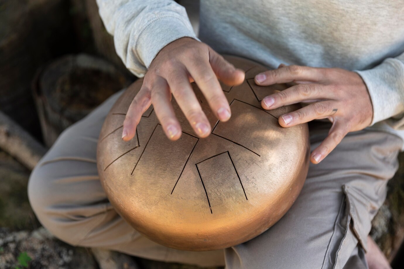 person playing a handpan, with both hands on the instrument