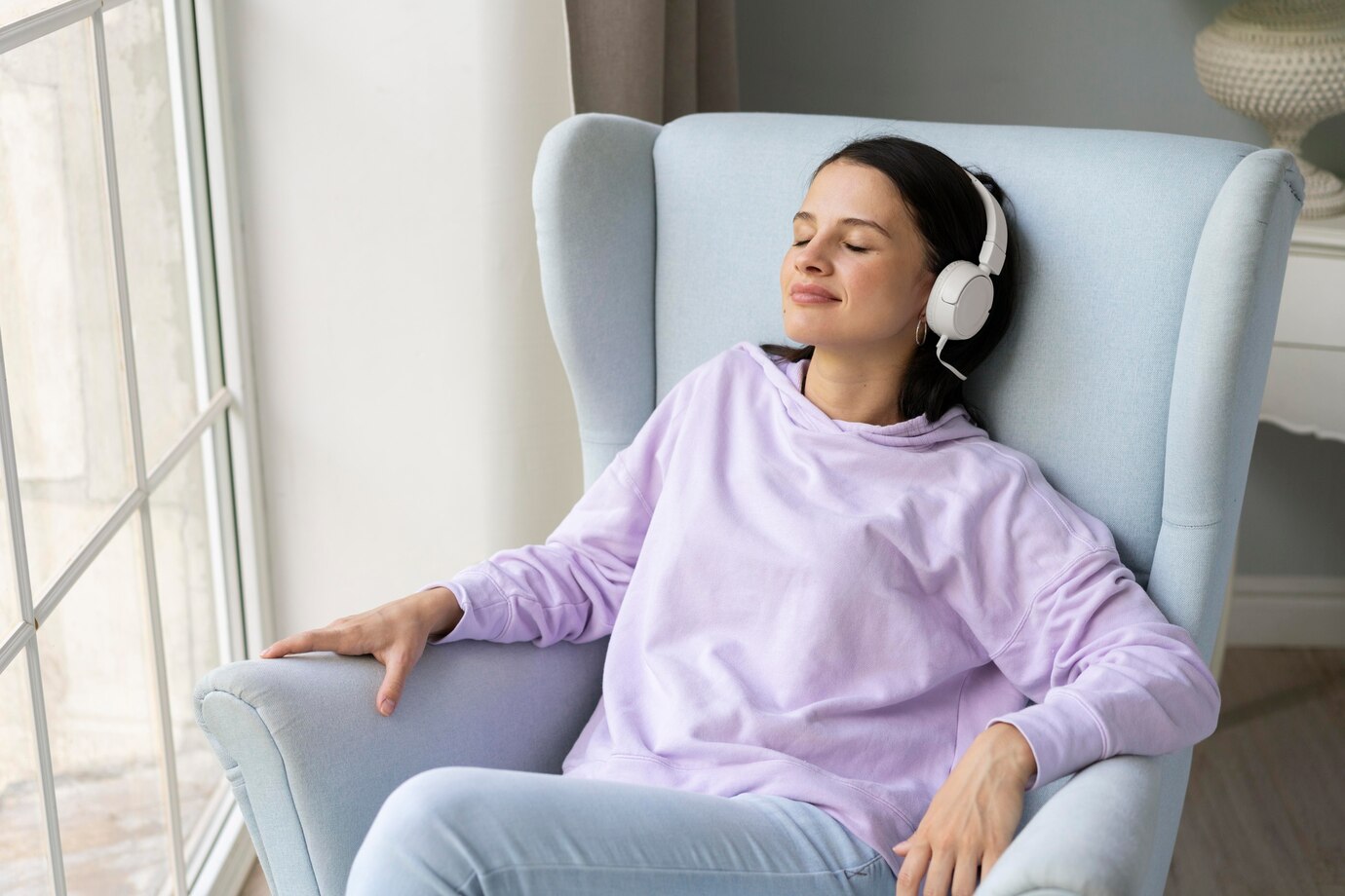 A person in a light purple sweatshirt relaxes in a blue armchair