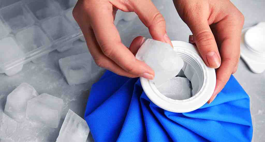 A person’s hands place an ice cube into a white container