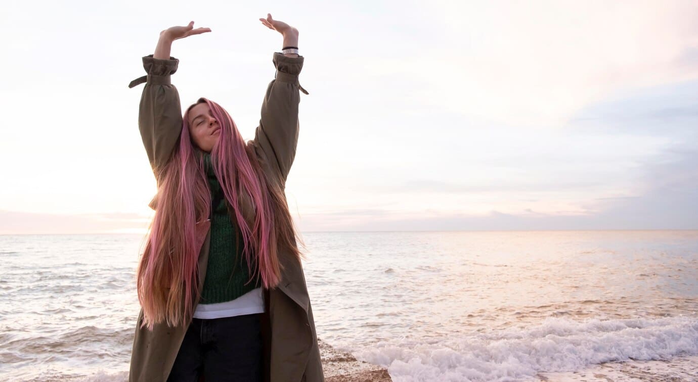 young woman with long pink hair joyfully stretching