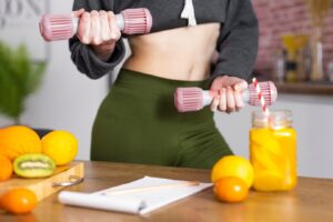 person in a cropped sweater and green leggings holds pink dumbbells