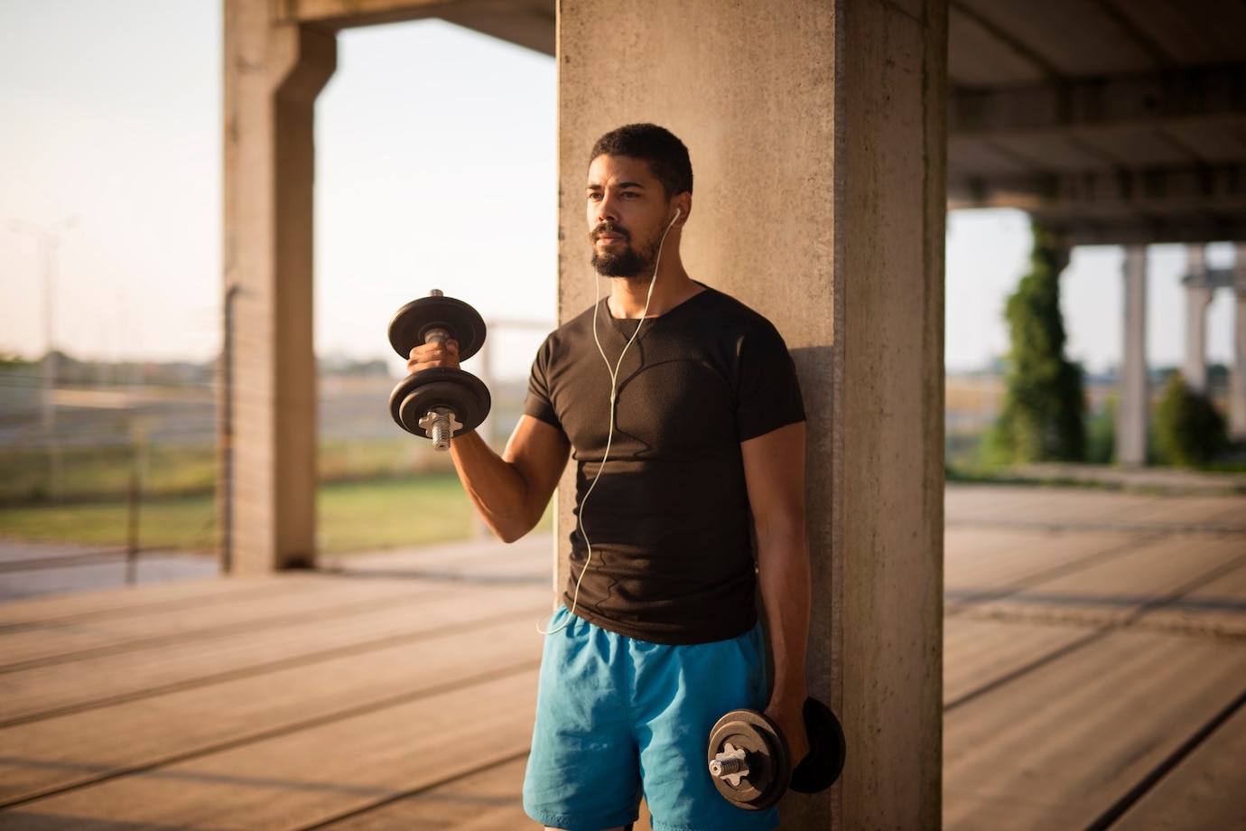  person in a black t-shirt and blue shorts holds dumbbells