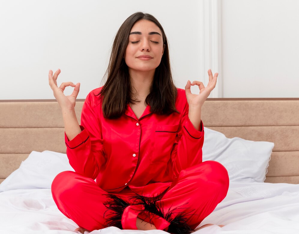 woman in a red pajama suit meditating in a cross-legged