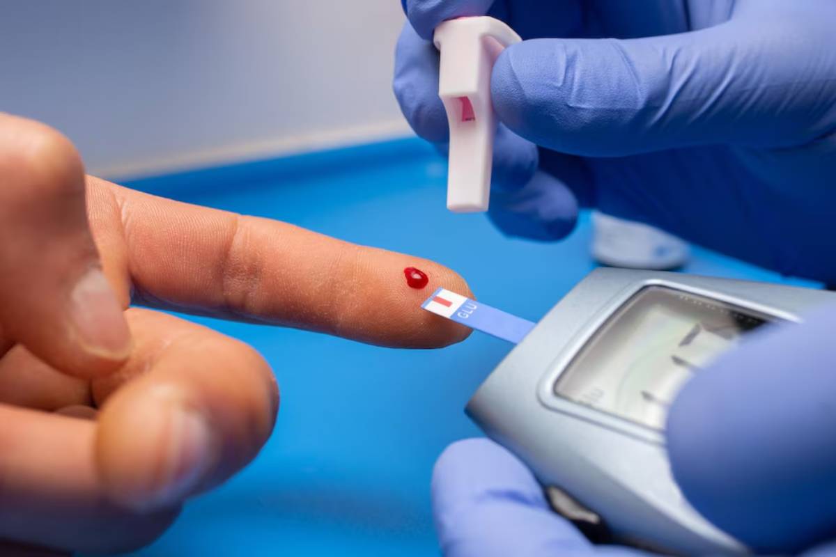 Healthcare professional testing blood glucose level from a drop of blood on a patient's fingertip.
